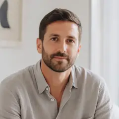Portrait de Josselin Labbé, cheveux bruns courts, barbe courte, chemise de lin gris galet, fond clair flou